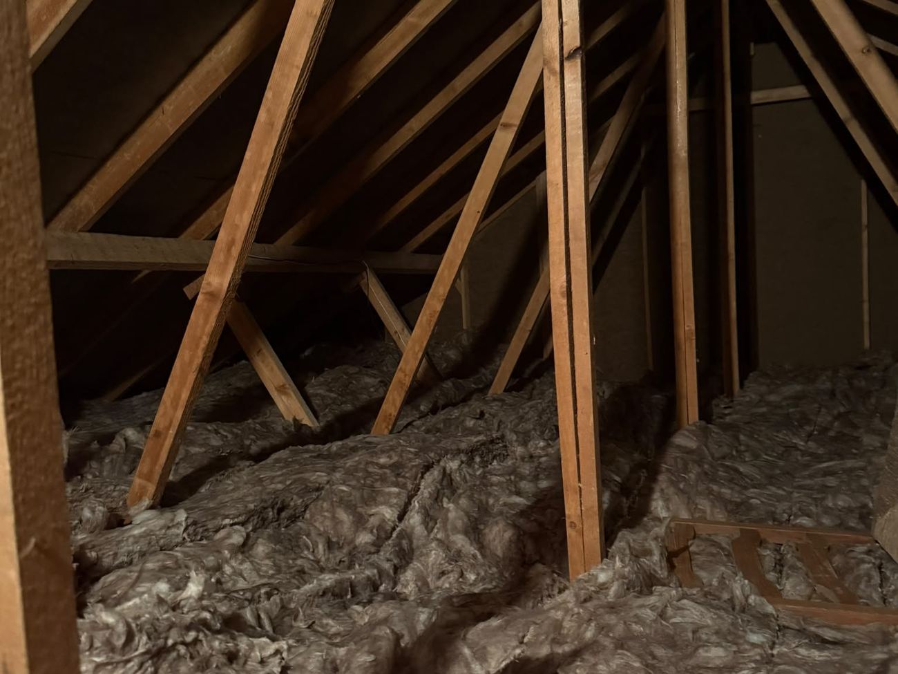 Settled and patchy mineral wool across the loft of a large Winchester bungalow before the top-up