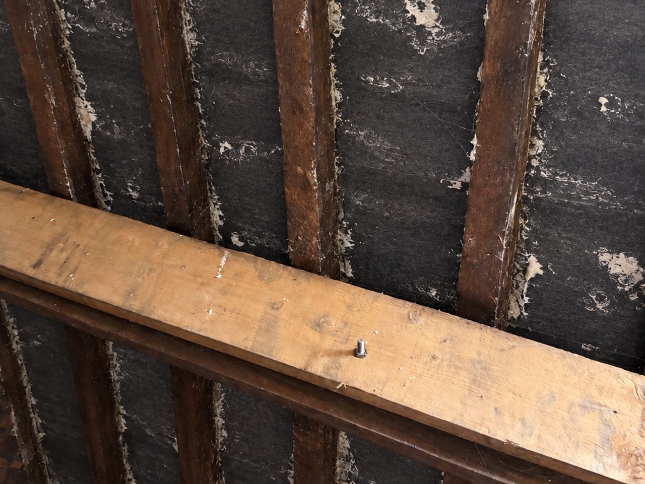 Rafters and roof felt stripped back during spray foam removal, with residue still being cleaned off