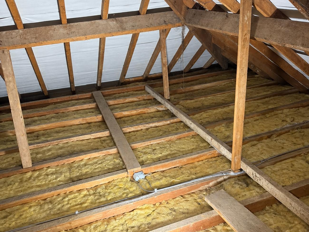 Farm loft before insulation work in Bridgend, old and disturbed fibre insulation