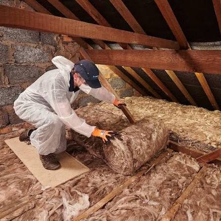 Installer rolling out mineral wool insulation across a loft floor