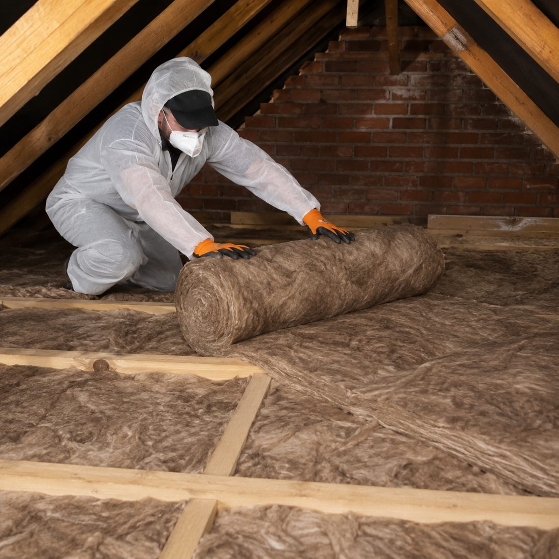 Installer laying a new roll of insulation over an existing loft floor